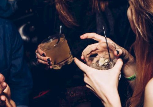 People are socializing, holding drinks and laughing, creating a lively and friendly atmosphere.