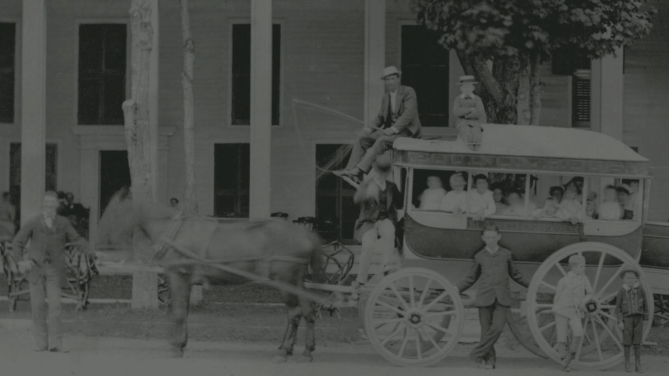 A vintage photo depicts a horse-drawn carriage with passengers and a driver, in front of a large building, possibly a hotel or residence, ending the sentence.
