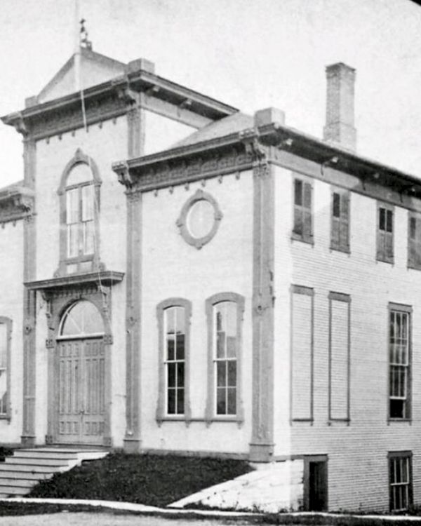 A historic two-story building with arched windows and a detailed facade stands, showcasing classic architectural features.